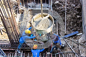 Worker pouring cement pouring into foundations formwork at building area in construction site