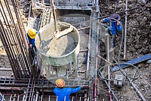 Worker pouring cement pouring into foundations formwork at building area in construction site
