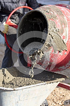 Worker pouring concrete with cement mixer at construction site, closeup