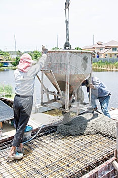 Worker pouring concrete works at construction site