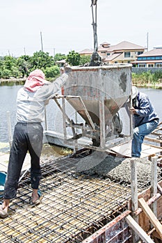 Worker pouring concrete works at construction site