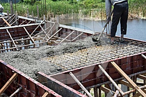 Worker pouring concrete works at construction site