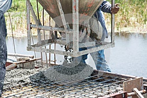 Worker pouring concrete works at construction site