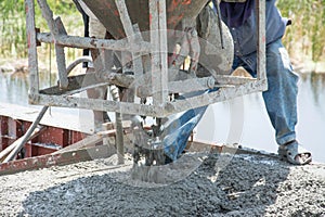 Worker pouring concrete works at construction site