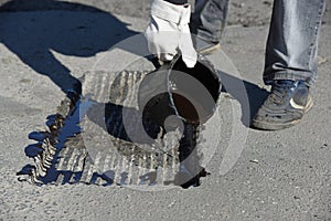 A worker pours tar on the edge of the road.