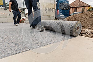 Worker prepares geotextile for the roof, covers it with synthetic membrane photo