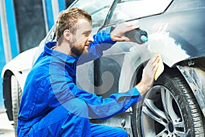 Worker preparing car body for paint