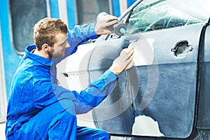 Worker preparing car body for paint