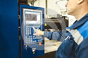 A worker presses a button and starts an automatic manufacturing process in a factory