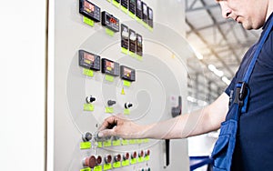 A worker presses a button and starts an automatic manufacturing process in a factory