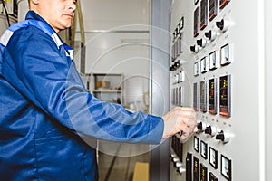 A worker presses a button and starts an automatic manufacturing process in a factory