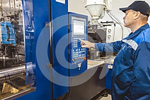 A worker presses a button and starts an automatic manufacturing process in a factory