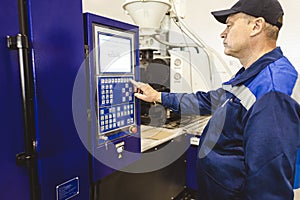 A worker presses a button and starts an automatic manufacturing process in a factory