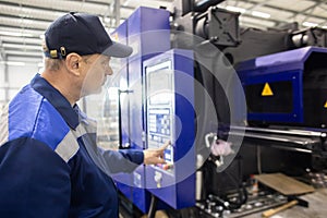 A worker presses a button and starts an automatic manufacturing process in a factory