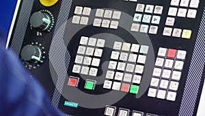 Worker presses buttons on machine control panel in workshop