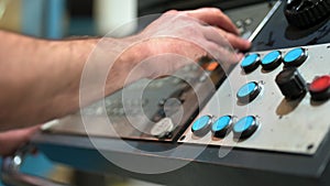 Worker pressing buttons on CNC machine control board in factory.