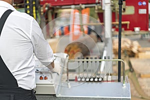 Worker pressing buttons on CNC machine control board in factory. Partially milled log on a portable lumber milling machine. photo