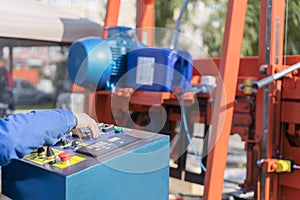 Worker pressing buttons on CNC machine control board in factory. Worker works at a woodworking enterprise. Hand on the machine