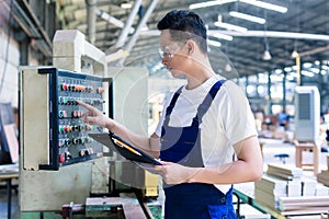 Worker pressing buttons on CNC machine in factory