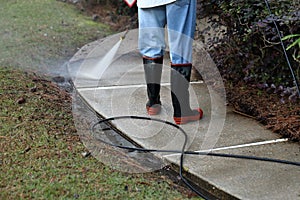 Worker pressure washing sidewalk