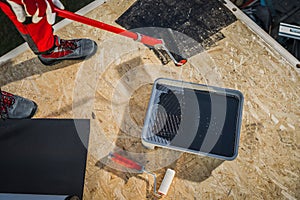 Worker Priming Plywood Roof before EPDM Membrane Installation