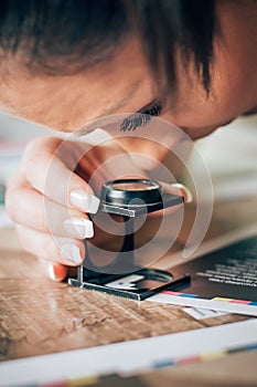 Worker in printing and press centar uses a magnifying glass