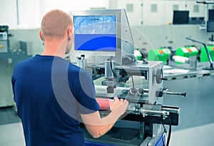 Worker in a printing and press center uses plate mounting machine to attach polymer relief plate on a printing cylinder.