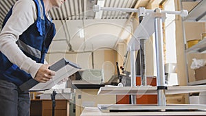 Worker of printing with a stack of paper at the machine