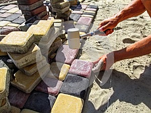 A worker in the process of laying multi-colored paving slabs