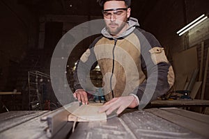A worker processes a Board on a woodworking machine
