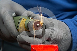 Worker processes metal with engraving drill close-up. The work of the dremel engraving electric tool. Industrial metal processing