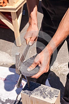 Worker produces roofing slate using a slate hammer. photo