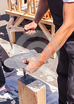 Worker produces roofing slate using a slate hammer. photo