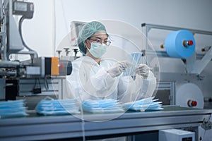 Worker producing surgical mask in modern factory, Covid-19 protection and medical concept