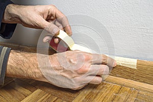 Worker protecting batten moulding with masking tape before paint