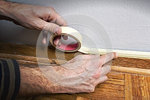 Worker protecting batten moulding with masking tape before paint