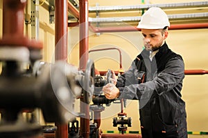 worker with protective helmet turns valve