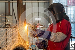 Worker with protective mask welding metal in factory