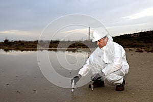 Worker in a protective suit examining pollution.