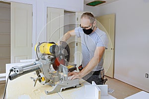 The worker protects himself from covid-19, man cut using circular saw rotating saw cutting wood baseboard
