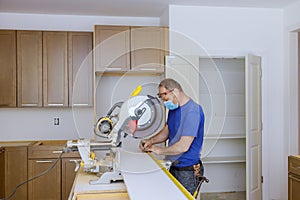 Worker protects himself from covid-19, man cut using circular saw rotating saw cutting wooden installation of in the kitchen of