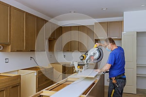 Worker protects himself from covid-19, man cut using circular saw rotating saw cutting wooden installation of in the kitchen of