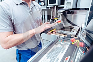 Worker pushing button to operate machine tool in manufacturing line