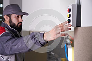 Worker pushing green button operating a machine in a factory, close up of hand