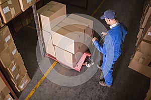 Worker pushing trolley with boxes in warehouse