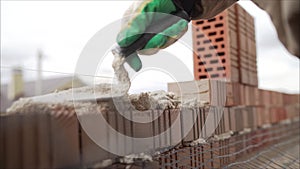 Worker puts a brick wall. Bricklayer working in construction site of a brick wall. Bricklayer putting down another row