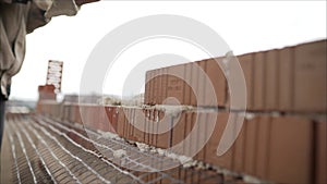 Worker puts a brick wall. Bricklayer working in construction site of a brick wall. Bricklayer putting down another row