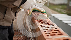 Worker puts a brick wall. Bricklayer working in construction site of a brick wall. Bricklayer putting down another row of bricks