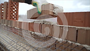Worker puts a brick wall. Bricklayer working in construction site of a brick wall. Bricklayer putting down another row of bricks