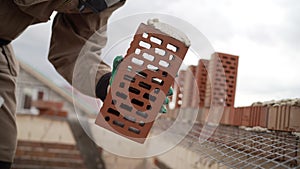 Worker puts a brick wall. Bricklayer working in construction site of a brick wall. Bricklayer putting down another row of bricks